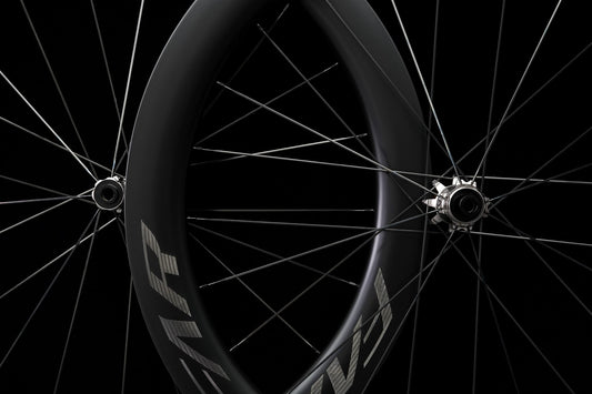 A carbon road wheel photographed on black, spokes and hub in view