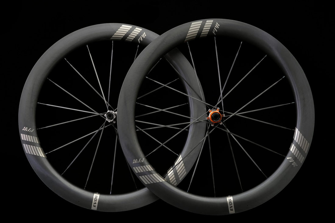 A pair of carbon road wheels on a black background, front and rear