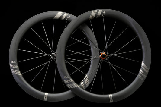 A pair of carbon road wheels on a black background, front and rear